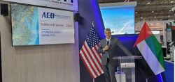 Erik Anderson standing behind a podium at the Dubai Airshow presenting about AED Aero.